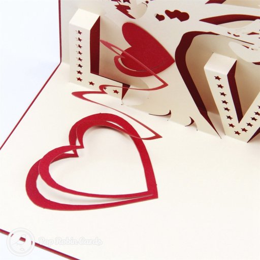 Pop-up love tree with two birds above cream star-cut letters spelling LOVE, and red hearts spiralling down the card