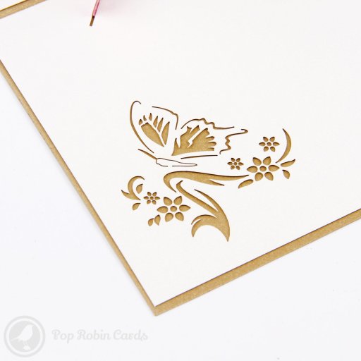 Two pop-up paper butterflies, one pale green and one pink, standing on white card pages with cut-out flower designs.