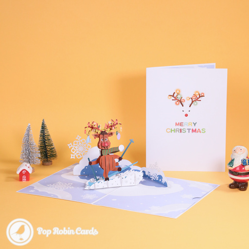 Rudolf the reindeer skiing in a 3D pop-up card, in a striped scarf with lit antlers, on a snowy slope with paper snowflakes