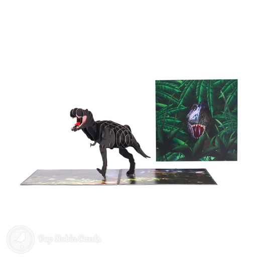 Pop-up T-Rex dinosaur with open jaws and a striped body of layered card, striding across a printed woodland floor of ferns.