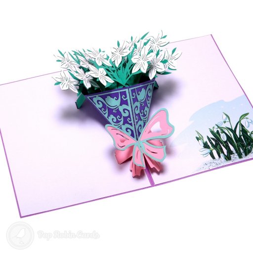 Pop-up bouquet of white flowers in a purple cone with a pink bow, beside printed snowdrops on the right-hand page