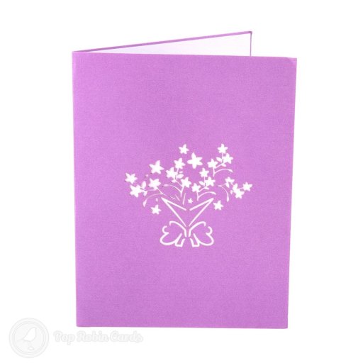 Pop-up bouquet of white flowers in a purple cone with a pink bow, beside printed snowdrops on the right-hand page